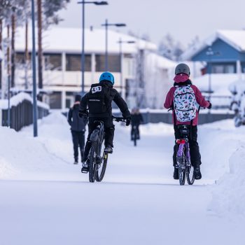 Kaksi lasta pyöräilee talvisessa kelissä.