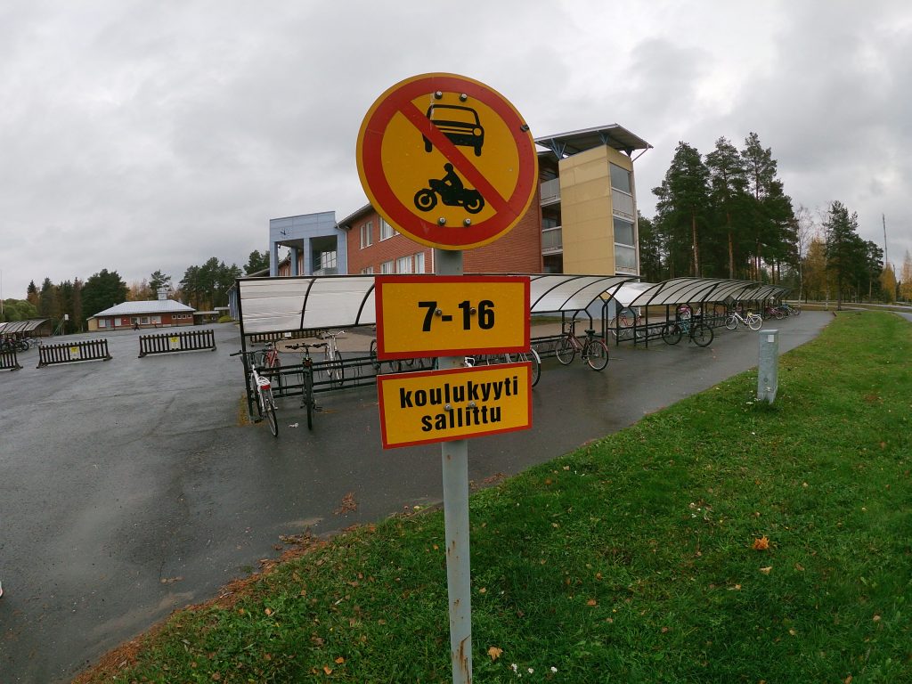 Koulutaksit ajavat suoraan koulun pihalle, pyöräparkkien välittömään läheisyyteen. Fiksusti kouluun -asiantuntijat ehdottivat koulutaksien noutopistettä ajotien reunaan koulun pihan sijasta.